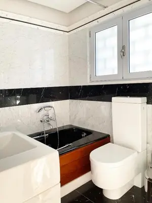 a bathroom with a tub and a toilet and a sink at Blue Bay Vouliagmeni Luxury Apartment in Athens