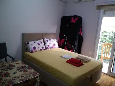a small bedroom with a bed with a headboard and a window at flower apartment-Hilton-US embassy in Athens