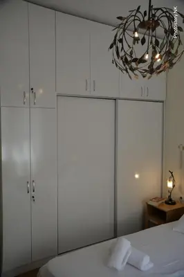 a bedroom with white cabinets and a chandelier at kynosargous square's apartment in Athens
