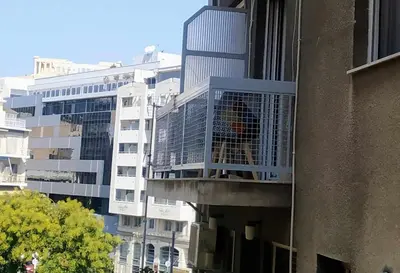 a bird in a cage on a balcony of a building at kynosargous square's apartment in Athens
