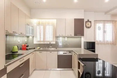 a kitchen with white cabinets and a clock on the wall at Filoxenia MG Projects Near Acropolis Veeikou in Athens