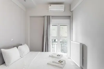 a white bedroom with a bed with two towels on it at Filoxenia MG Projects Near Acropolis Veeikou in Athens