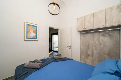 a bedroom with a blue bed with a clock on the wall at The Dona House in Vaia