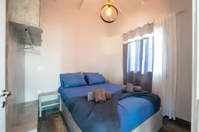 a bedroom with a bed with blue sheets and a window at The Dona House in Vaia