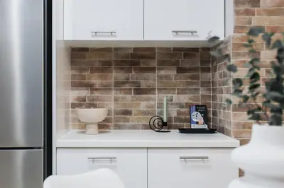 a kitchen with white cabinets and a brick wall at Gorgeous 1BR Apartment in Kolonaki by UPSTREET in Athens