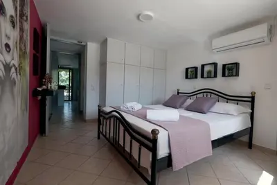 a bedroom with a large bed with white sheets and purple pillows at Ellie's StoneHouse Gianapa, Porto Rafti, Greece, 190 03, GR in Porto Rafti