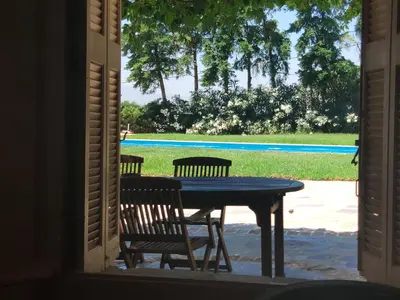 a table and chairs in a porch with a view of a pool at Ellie's StoneHouse Gianapa, Porto Rafti, Greece, 190 03, GR in Porto Rafti