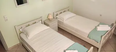 two twin beds in a room with a lamp at Ellie's StoneHouse Gianapa, Porto Rafti, Greece, 190 03, GR in Porto Rafti