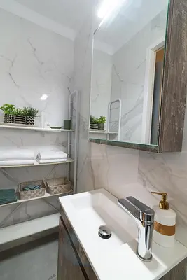 a white bathroom with a sink and a mirror at jack daniel's appartment in Athens