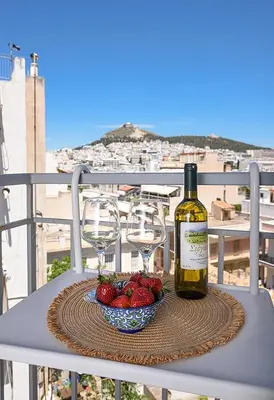 a bottle of wine and a bowl of strawberries on a table at jack daniel's appartment in Athens