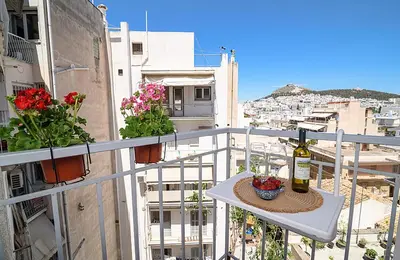 a balcony with a table with a bottle of wine and flowers at jack daniel's appartment in Athens