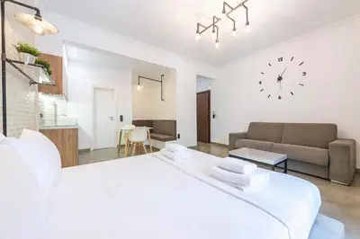 a white bedroom with a large bed and a couch at Stylish 1BR apartment in the heart of Koukaki in Athens