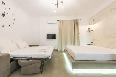 a white bedroom with a bed and a couch at Stylish 1BR apartment in the heart of Koukaki in Athens