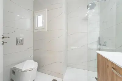 a white bathroom with a toilet and a shower at Stylish 1BR apartment in the heart of Koukaki in Athens