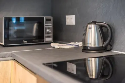 a tea kettle on a counter next to a microwave at Newly renovated apt in the heart of Kerameikos in Athens
