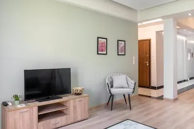 a living room with a flat screen tv and a chair at 2 Bedroom condo with dream balcony in Athens