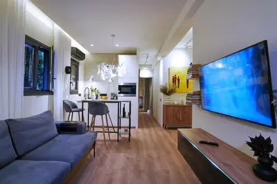 a living room with a couch and a tv on a wall at P Faliro Riviera Suite in Athens