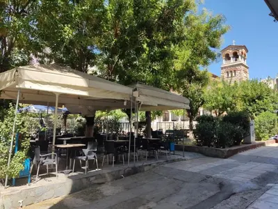 a restaurant with tables and chairs under aige umbrella at PURE URBAN ACROPOLIS METRO PETRALONA in Athens