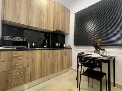 a kitchen with wooden cabinets and a black table and chair at Our little 1 in Athens