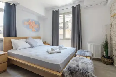 a bedroom with a bed and a chair and a window at Nereid Apartment in Athens