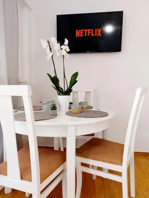 a white table with two chairs and a vase with white flowers at Lovely equipped apartment in Kallithea Athens in Athens