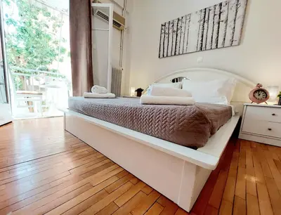 a white bed in a room with a wooden floor at Lovely equipped apartment in Kallithea Athens in Athens