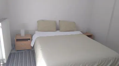 a bedroom with a large white bed and a night stand at Modern apartment near Acropolis peaceful location. in Athens