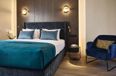 a bedroom with a bed and a blue chair at Acropolis Panorama Residence in Athens