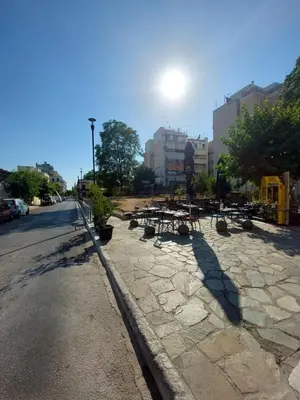 a sidewalk with tables and chairs on a city street at Kerameikos residence in Athens