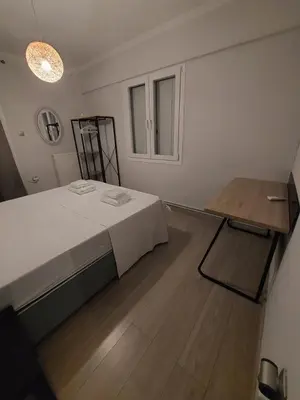 a white room with a bed and a wooden table at Blue Flag Glyfada Center in Athens