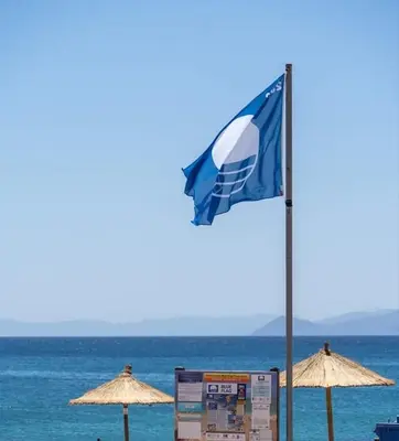 a blue flag on a beach with umbrellas at Blue Flag Glyfada Center in Athens