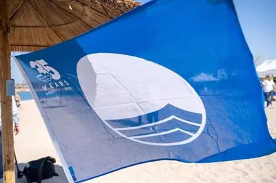 a blue and white sign on the beach at Blue Flag Glyfada Center in Athens