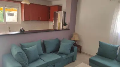 a living room with a blue couch and a kitchen at Evelina's suite in Artemida