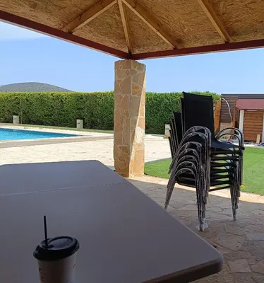 a table and chairs on a patio with a pool at Evelina's suite in Artemida