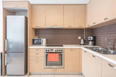 a kitchen with wooden cabinets and a stainless steel refrigerator at Elegant Home with Balcony by CloudKeys in Athens