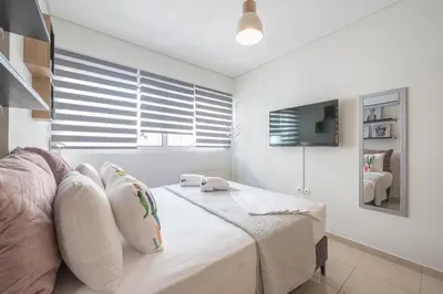a white bedroom with a bed with pillows and a tv at Elegant Home with Balcony by CloudKeys in Athens