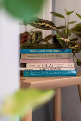 a stack of books on a table with a potted plant at Athenian Serene City Escape in Athens