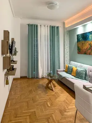 a living room with a couch and a wooden floor at Cozy and Chic apartment in the Center, 5 min Subway in Athens
