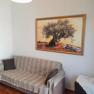 a couch in a living room with a painting on the wall at Success's Apartment in Athens