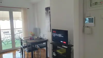 a living room with a table with a television and a dining room at Success's Apartment in Athens