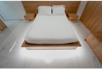 a white bed sitting on a wooden platform in a room at Luxury Studio in the heart of Kolonaki in Athens