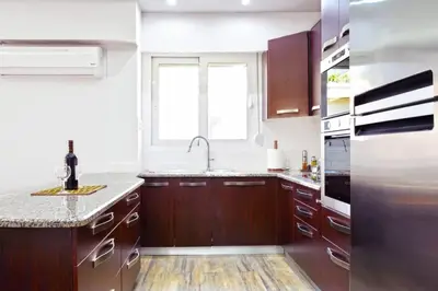 a kitchen with wooden cabinets and a sink and a window at Luxury at its best beach condo in Palaio Faliro in Athens