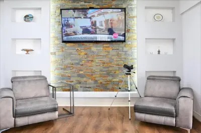 a living room with two chairs and a tv on a brick wall at Luxury at its best beach condo in Palaio Faliro in Athens