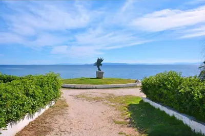 a dirt road with a statue in front of the ocean at Luxury at its best beach condo in Palaio Faliro in Athens
