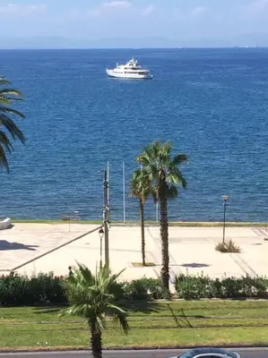 a cruise ship in the ocean with palm trees at Finer Things Flisvos Beach Condo in Palaio Faliro in Athens