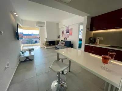 a kitchen with a counter and a living room at Sparkling dream in Saronida