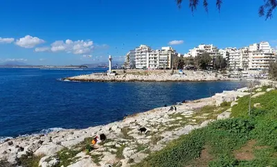 a group of people sitting on the rocks near the water at Casa Nova - Appartment near the sea in Piraeus