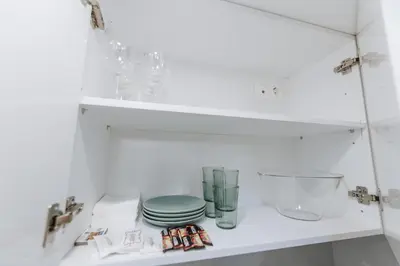 a white cabinet with plates and glasses on a shelf at Your Cozy Sapphire Apartment VIPGreece in Athens