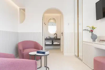 a living room with pink chairs and a table and a mirror at Altar Suites in Athens
