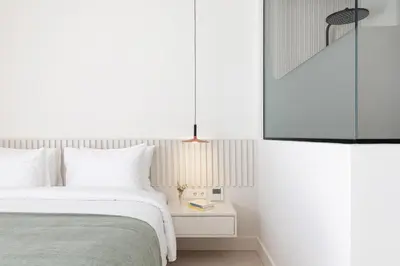 a white bedroom with a bed and a nightstand at Altar Suites in Athens